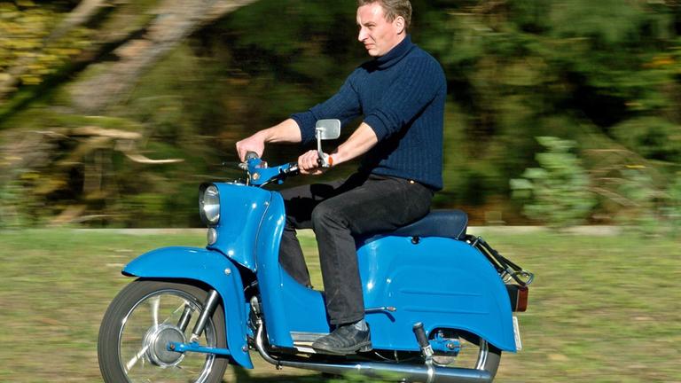 Ein Mann fährt den Motorroller Schwalbe in blau.