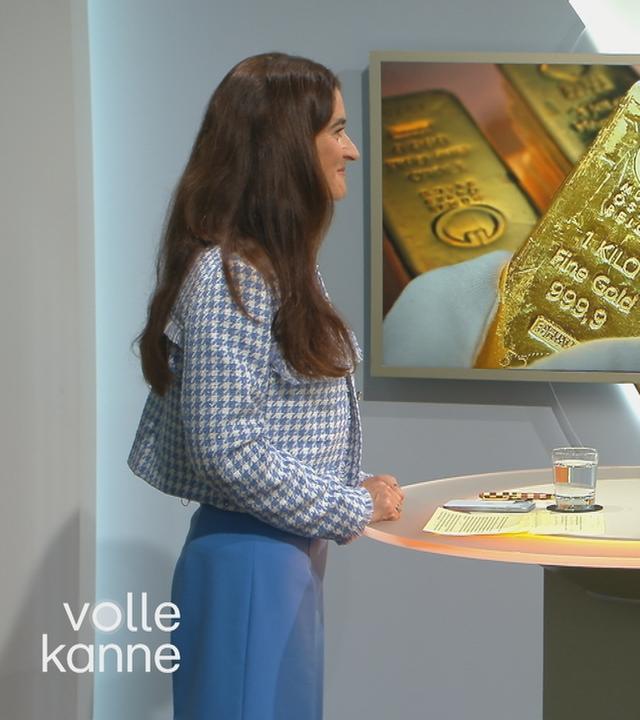 Sina Mainitz im Gespräch mit Florian Weiss, im Hintergrund ein Bild mit Goldbarren.