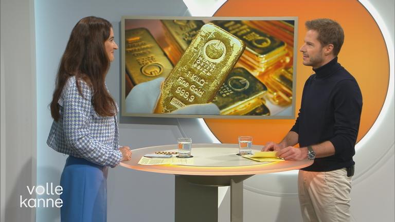 Sina Mainitz im Gespräch mit Florian Weiss, im Hintergrund ein Bild mit Goldbarren.