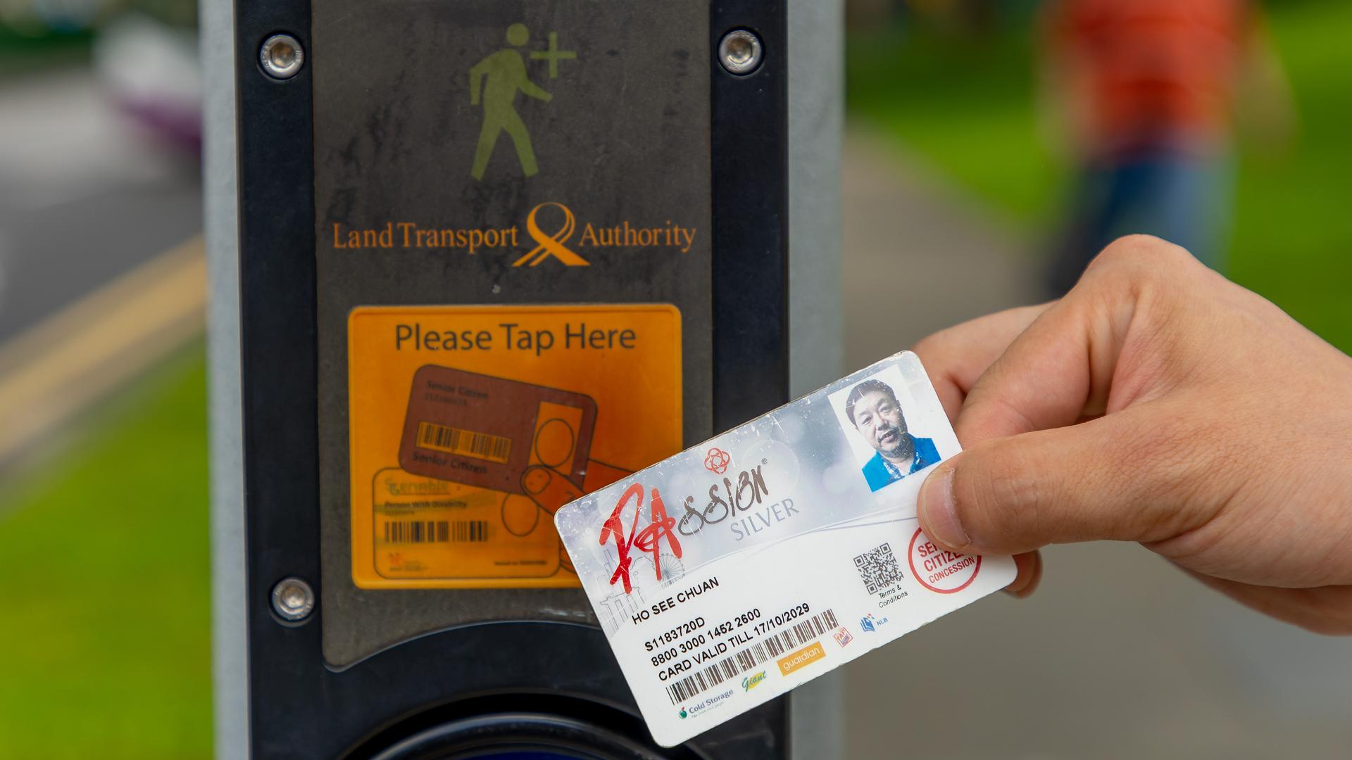 In Singapur hält eine Person einen Ausweis an eine Ampel für Senioren.