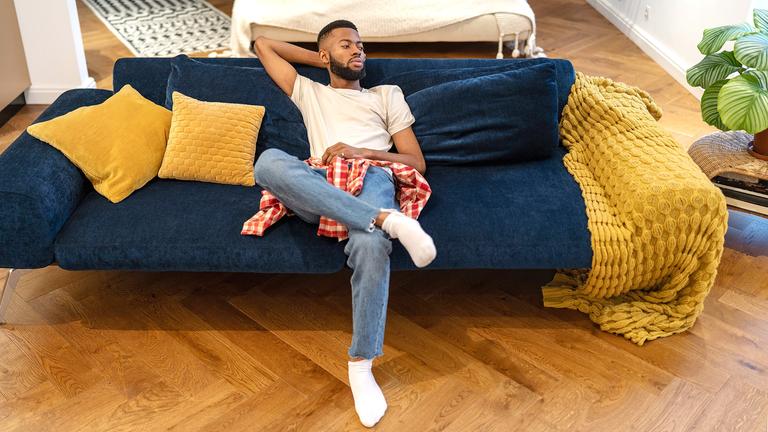 Ein Mann sitzt auf Sofa im Studio-Apartment