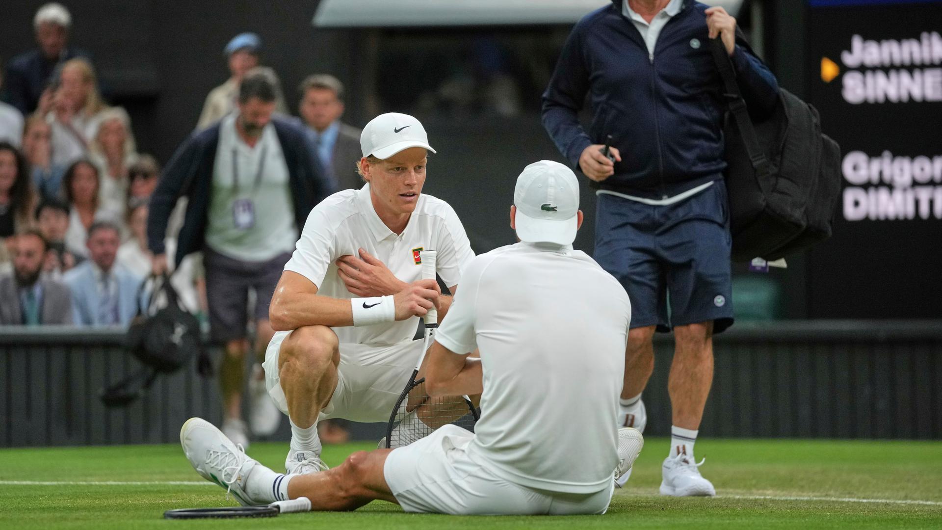 Italiens Jannik Sinner geht zu Bulgariens Grigor Dimitrow, nachdem dieser das Spiel wegen einer Verletzung abbrechen musste.