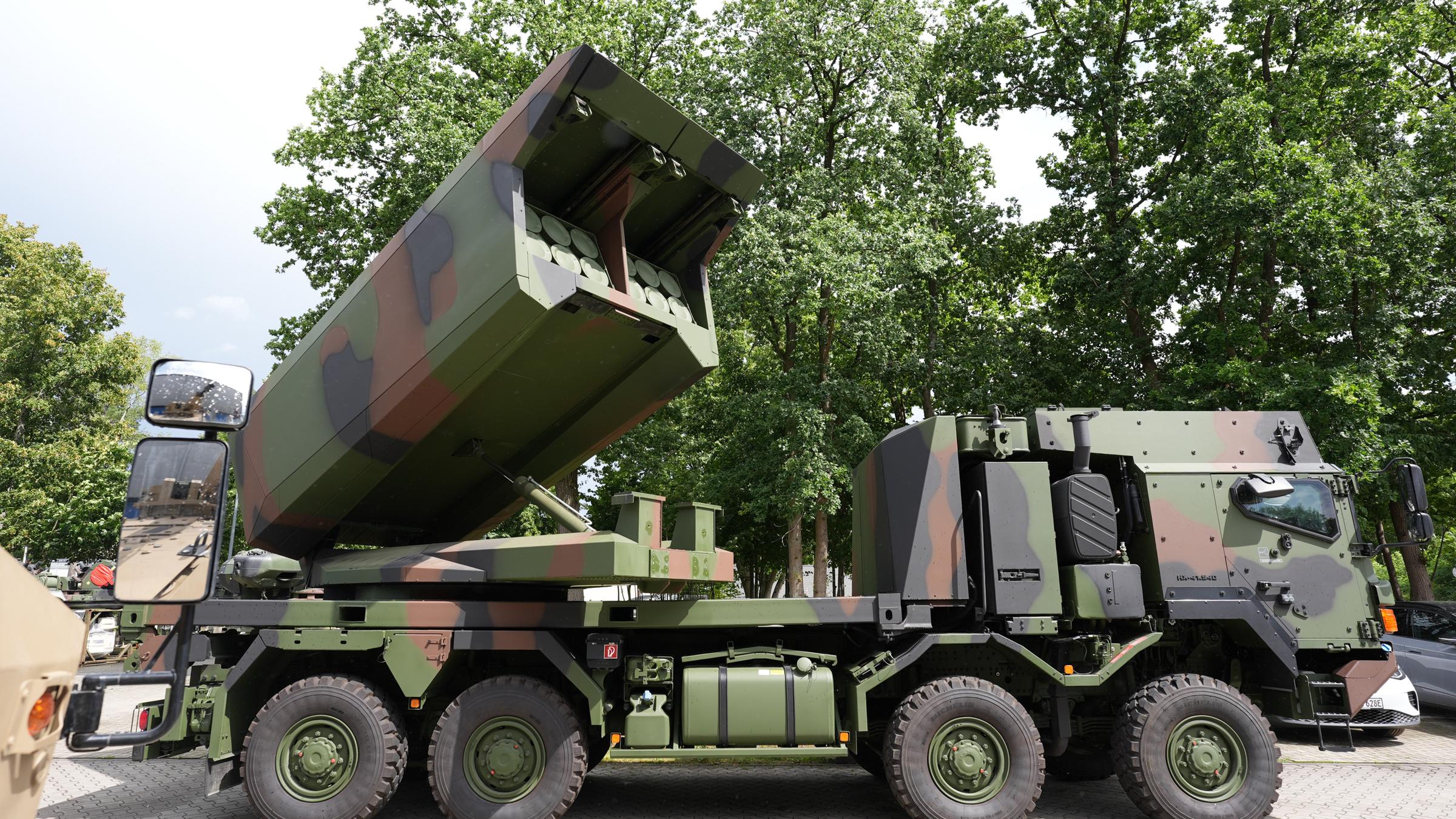 Ein Mehrfachraketenwerfer auf einem LKW in Camoufalge steht auf einem Parkplatz.