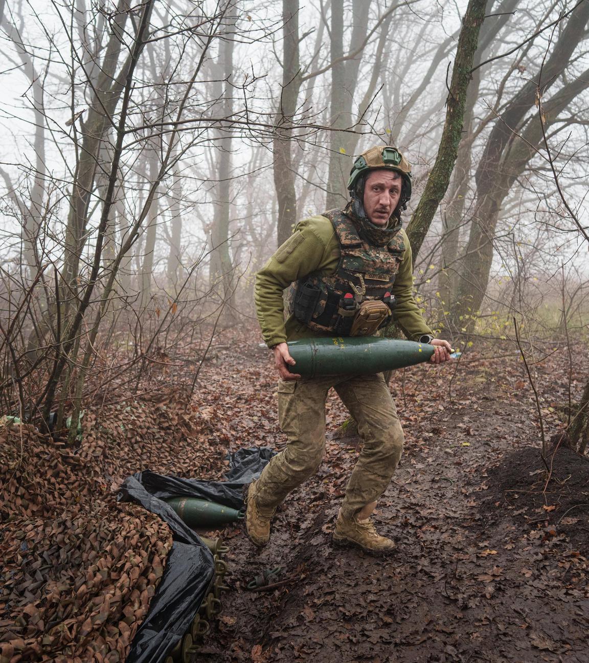 Ein ukrainischer Soldat des Bataillons Da Vinci Wolves trägt eine Artilleriegranate, bevor er auf russische Stellungen an der Frontlinie in der Ostukraine feuert. 