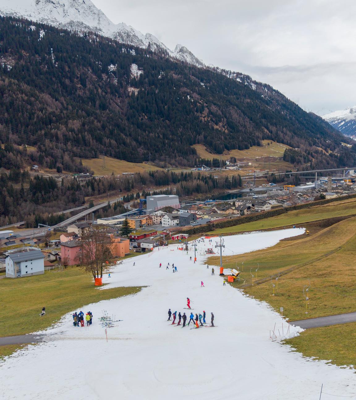 Skifahrer auf einem schmalen Streifen künstlichem SChnee in den Schweizer Alpen.
