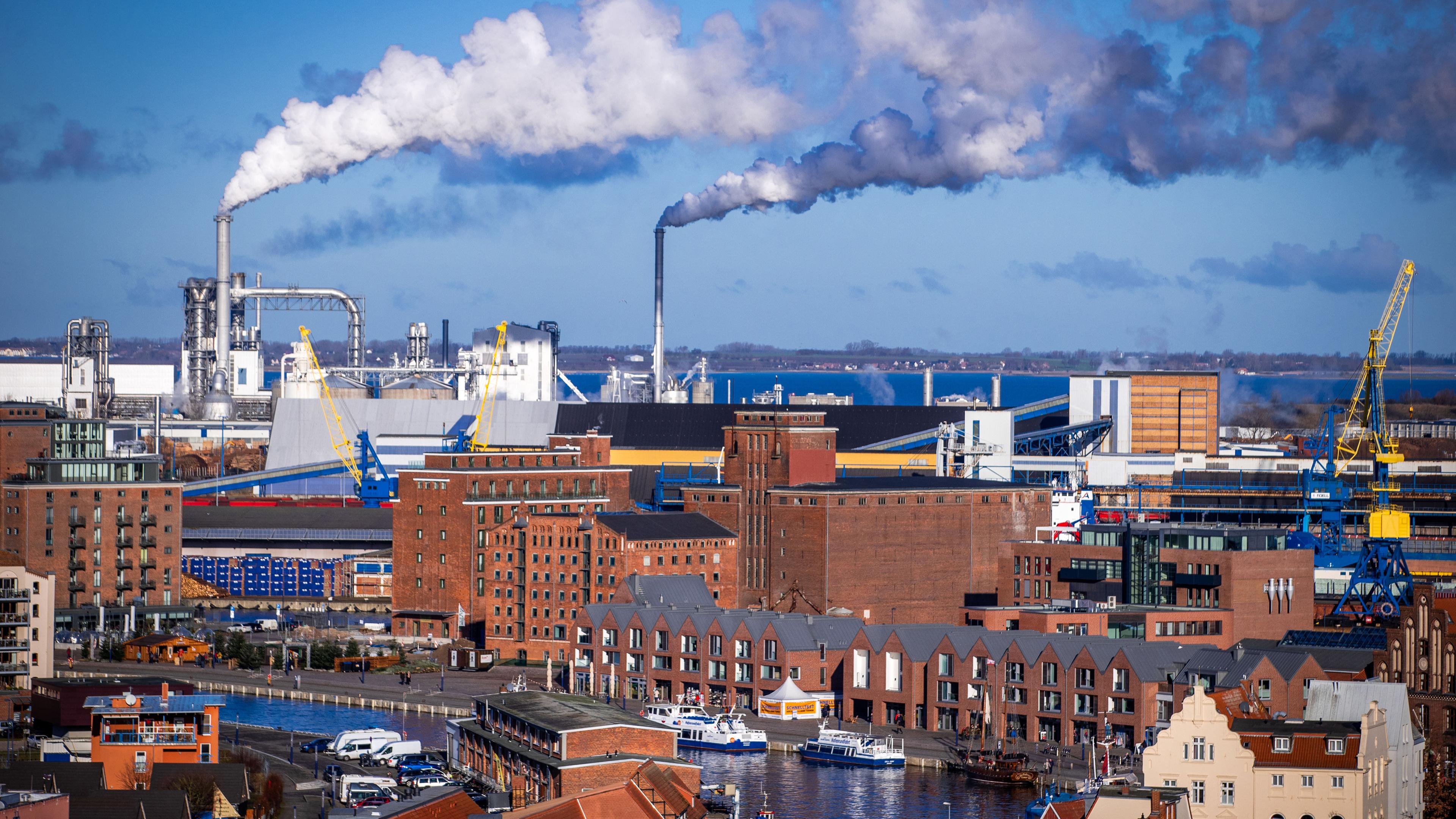 Mecklenburg-Vorpommern, Wismar: Rauch steigt aus Schornsteinen von holzverarbeitenden Industriebetrieben am Seehafen Wismar auf.