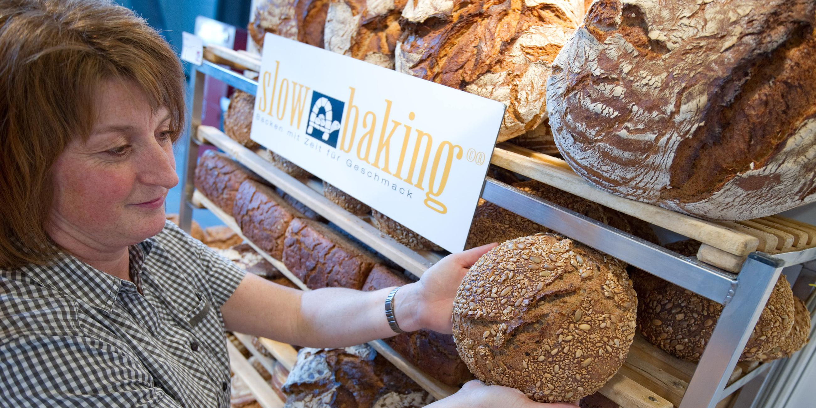Eine Mitarbeiterin sortiert am zu Beginn der Messe "Slow Food" am Stand einer Bäckerei einen Laib Brot in ein Regal. 