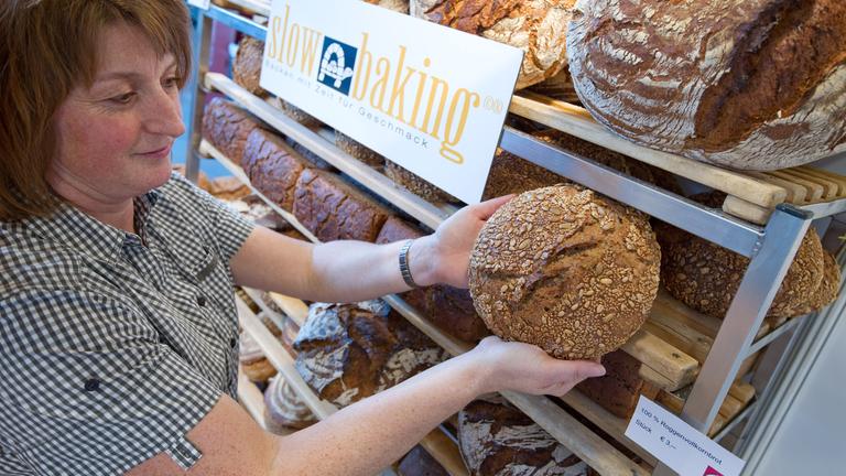Eine Mitarbeiterin sortiert am zu Beginn der Messe "Slow Food" am Stand einer Bäckerei einen Laib Brot in ein Regal. 