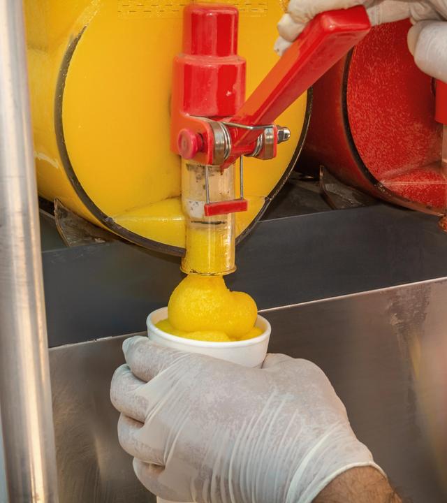 Ein Verkäufer zapft Slush-Eis aus einer Maschine in einen Trinkbecher ab.
