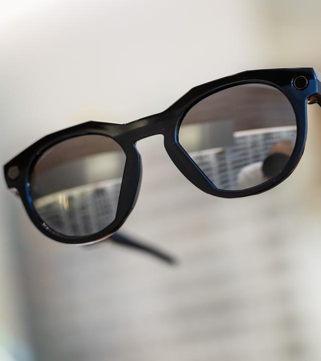 Eine Hand hält eine smarte Datenbrille in einem Geschäft hoch.