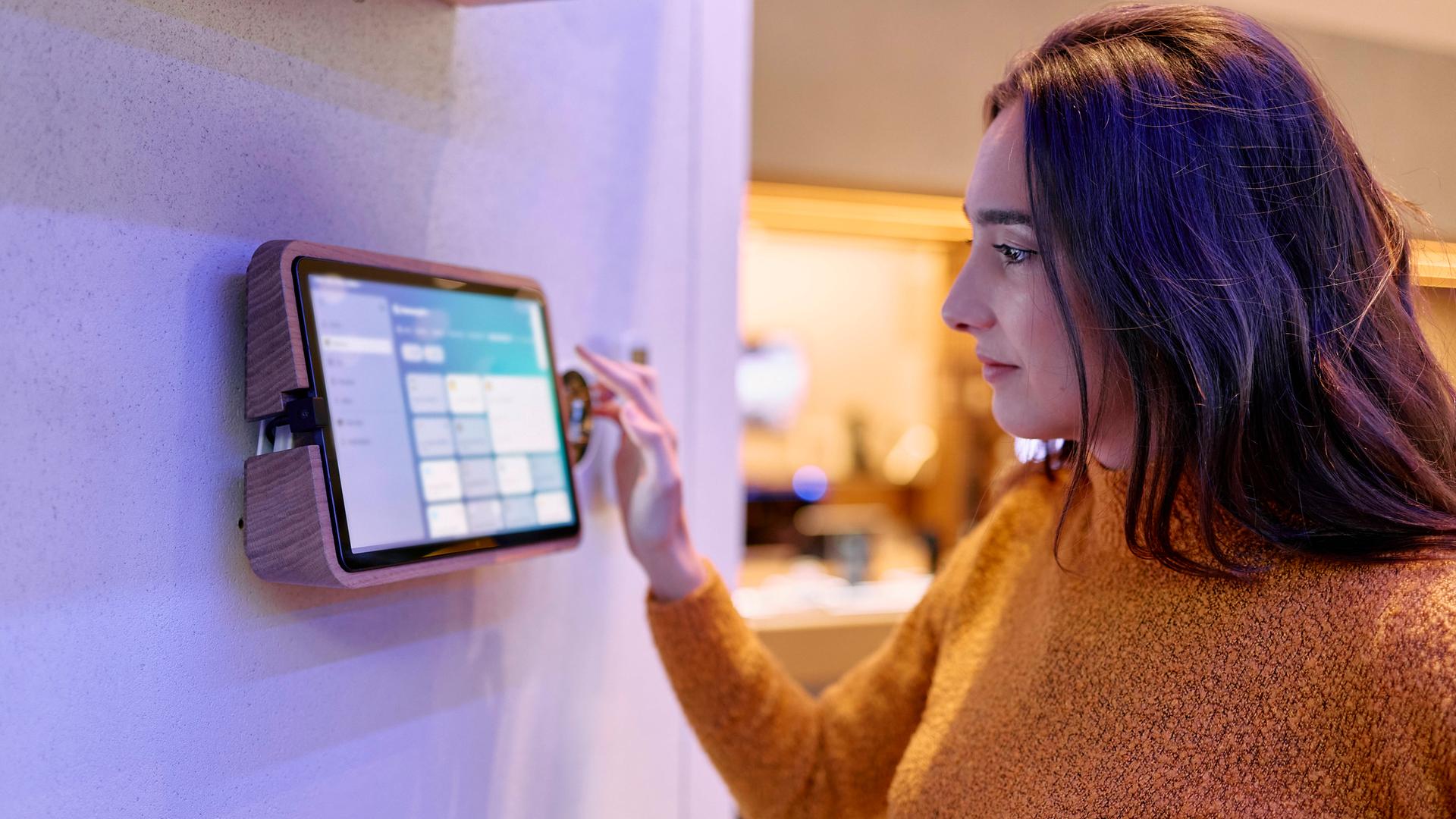Frau steuert Smart-Home-Anwendungen via Touch Screen.