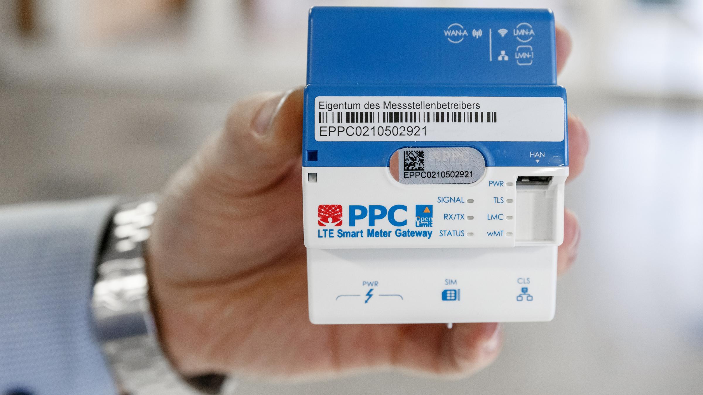ne Hand hält ein Smart-Meter-Gateway zur Übertragung der Stromverbrauch-Daten von digitalen Stromzählern.