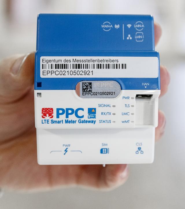 ne Hand hält ein Smart-Meter-Gateway zur Übertragung der Stromverbrauch-Daten von digitalen Stromzählern.