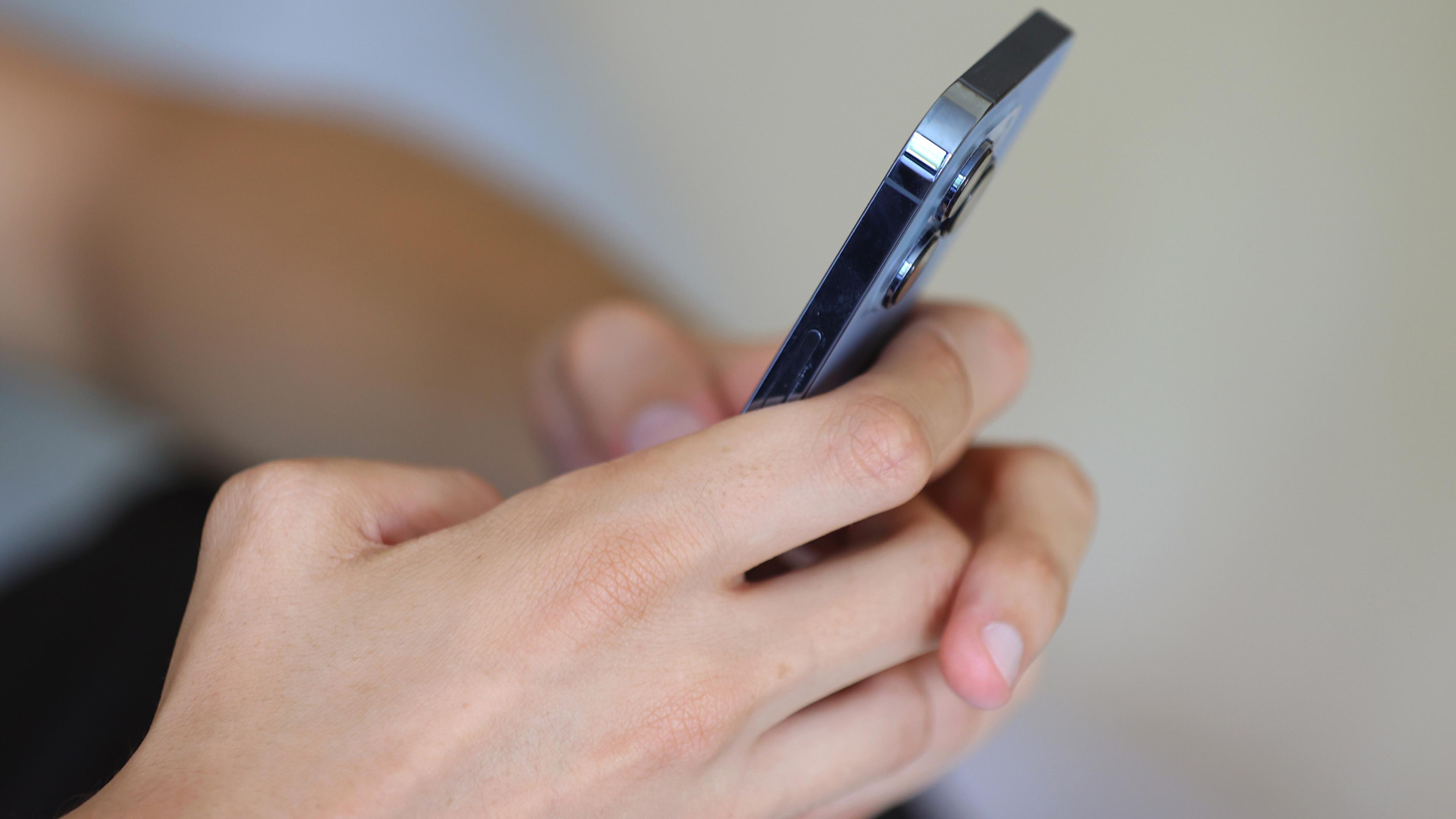 Ein Jugendlicher hält ein Smartphone in den Händen.