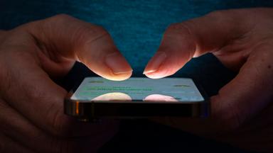 Symbolbild: Frau tippt auf einem Apple iPhone13 Smartphone-Screen SMS