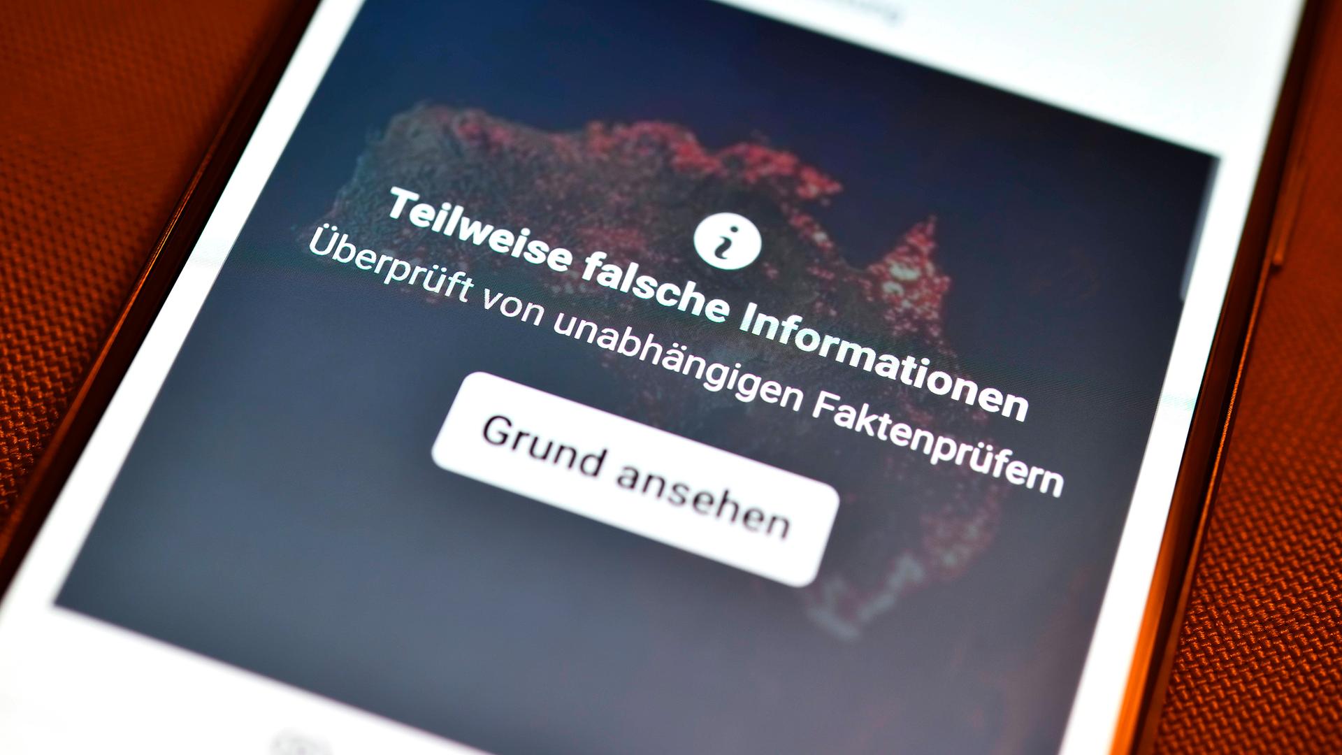 Smartphone mit aufgedeckter Falschinformation in einem sozialen Netzwer