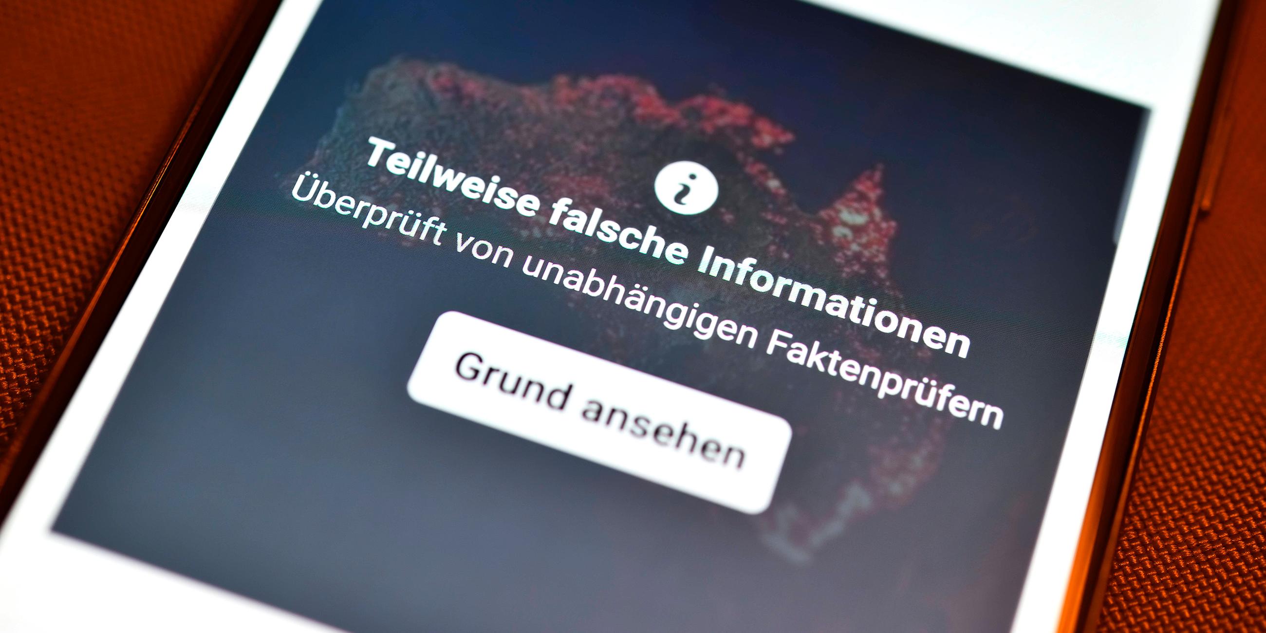 Smartphone mit aufgedeckter Falschinformation in einem sozialen Netzwer