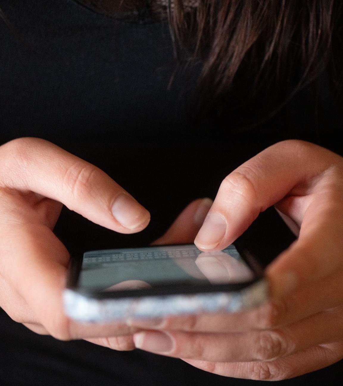 Eine Jugendliche tippt auf einem Smartphone