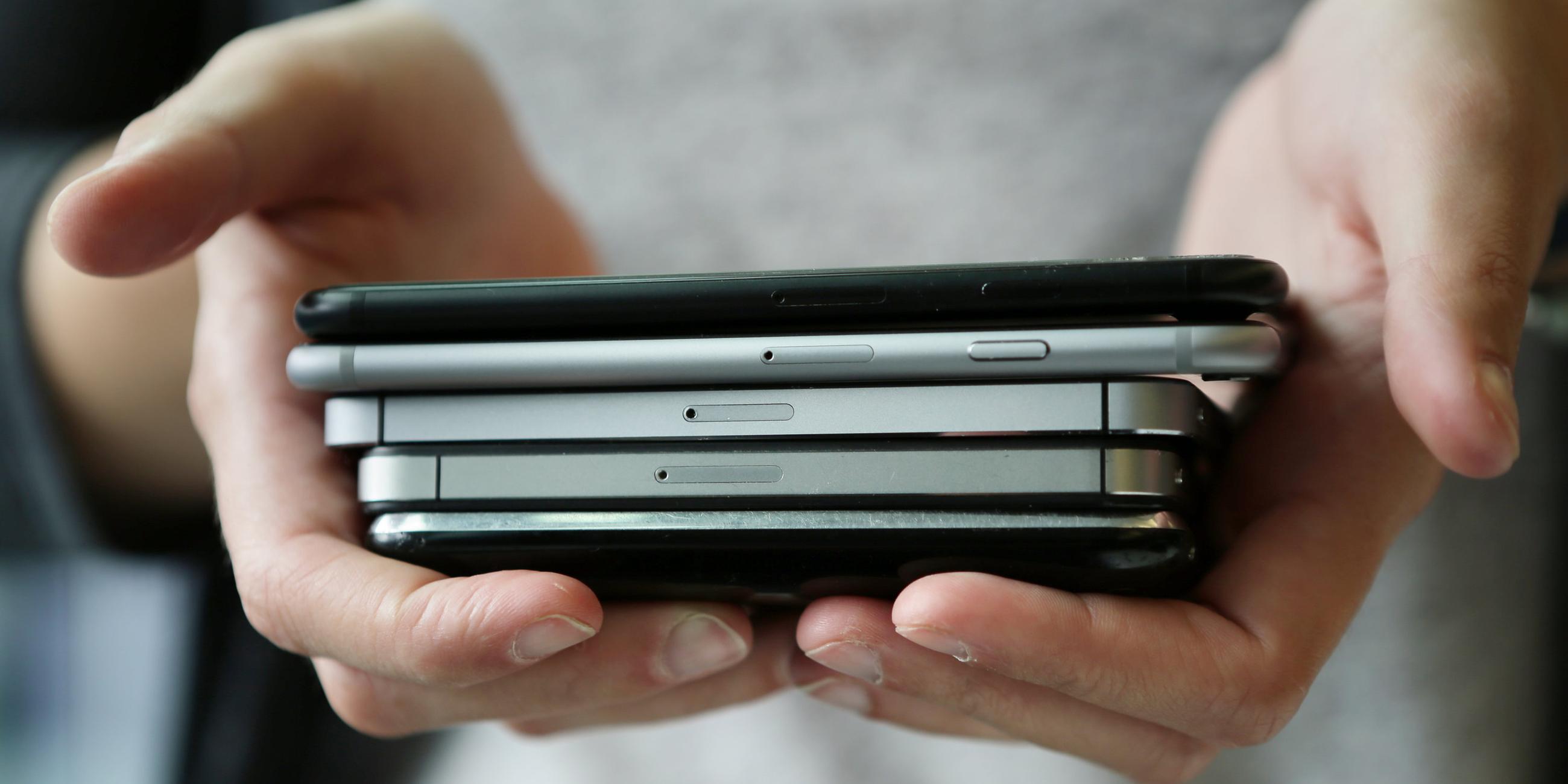 Eine Frau hält mehrere Modelle von Smartphones in den Händen.