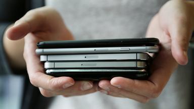 Eine Frau hält mehrere Modelle von Smartphones in den Händen.