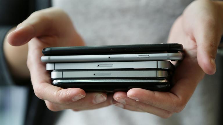 Eine Frau hält mehrere Modelle von Smartphones in den Händen.