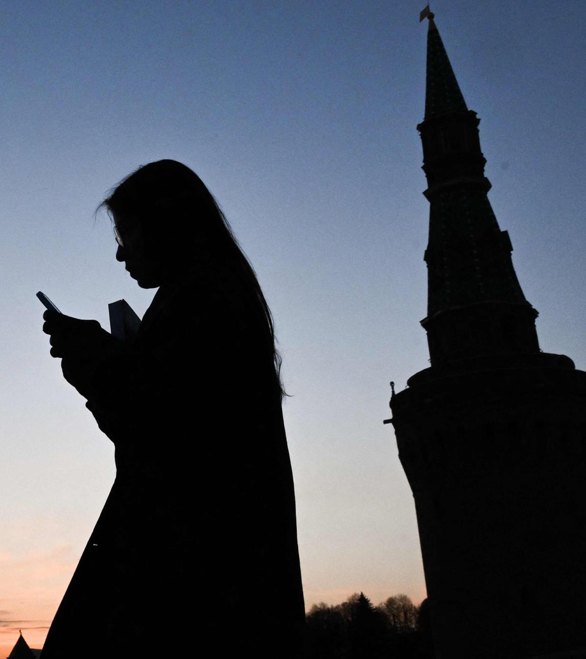 Eine Frau benutzt ihr Smartphone und läuft über die Moskvoretsky Brücke in Moskau.