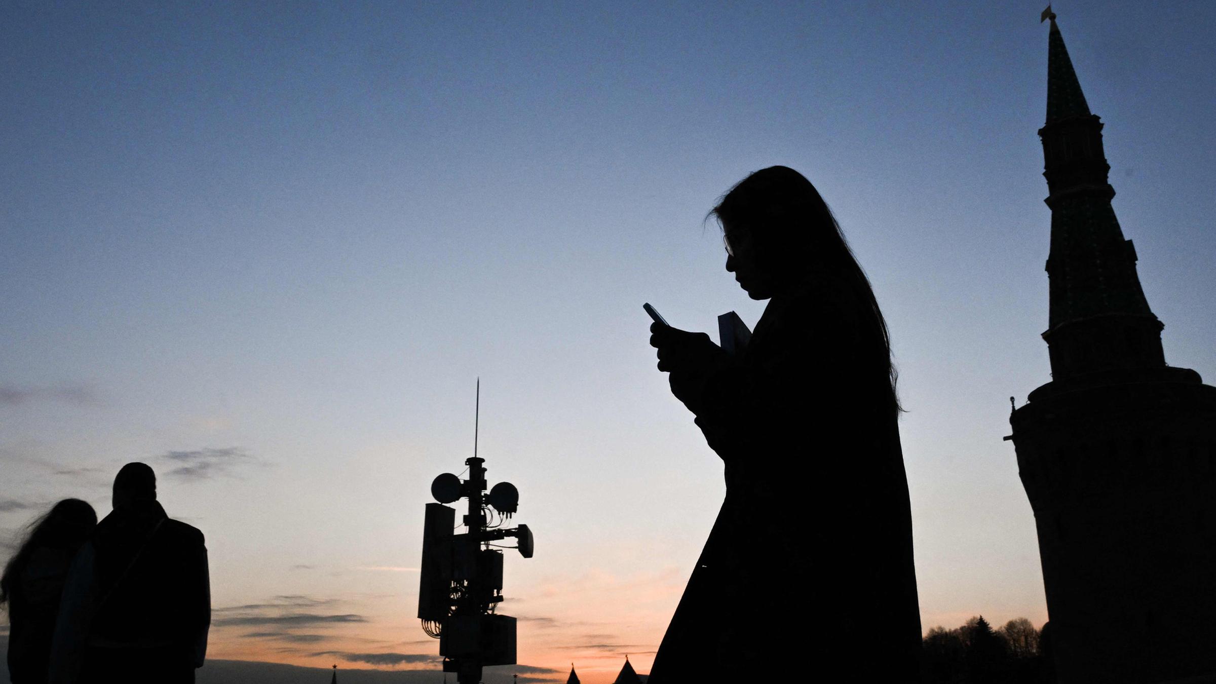 Eine Frau benutzt ihr Smartphone und läuft über die Moskvoretsky Brücke in Moskau.