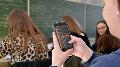 Hessen, Fulda: Schülerin nutzt auf ihrem Handy während des Unterrichts eine Physik-App.