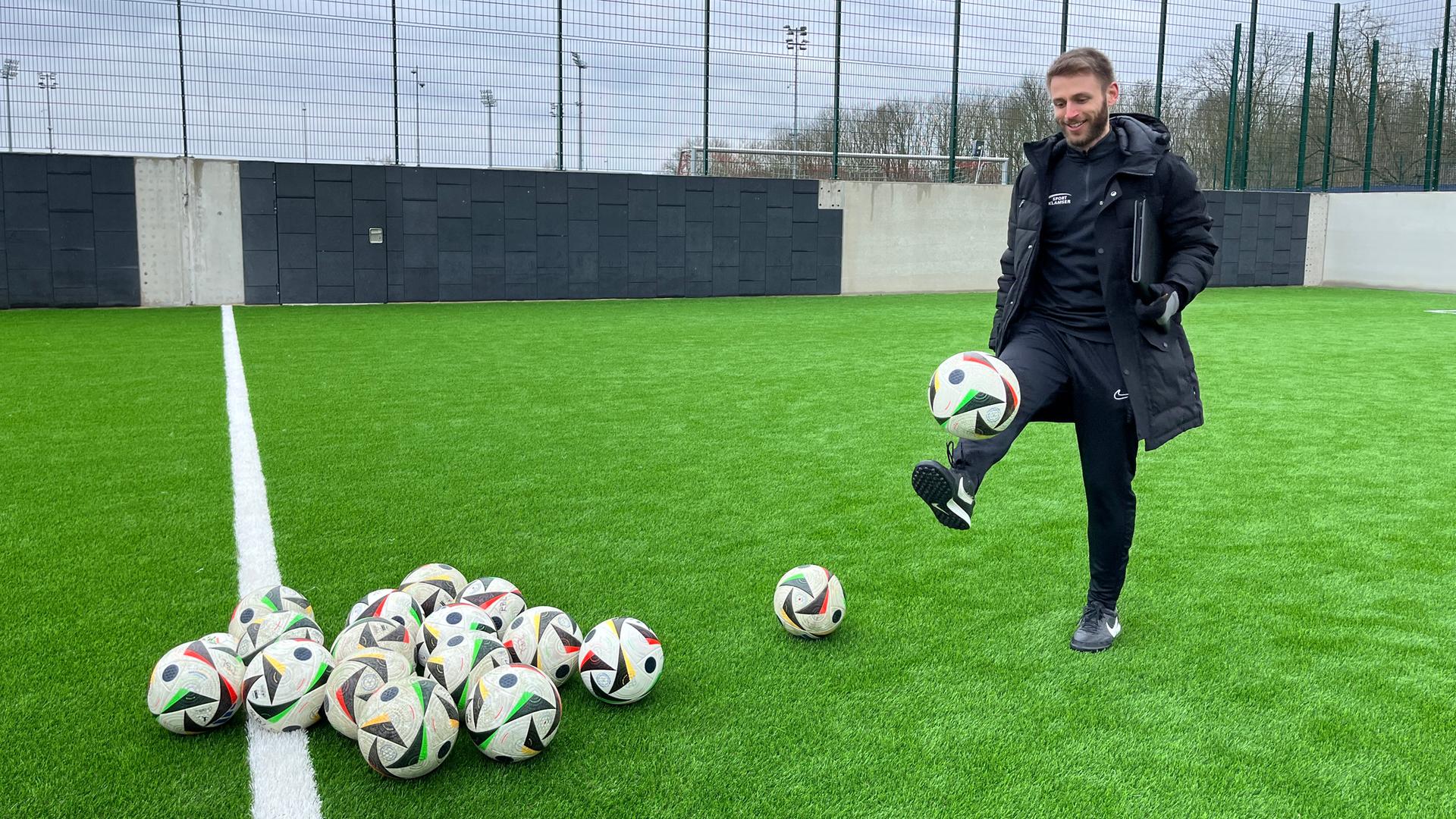 Simon Jans, der Gründer von Soccerkinetics, balanciert einen Fußball auf seinem Fuß.