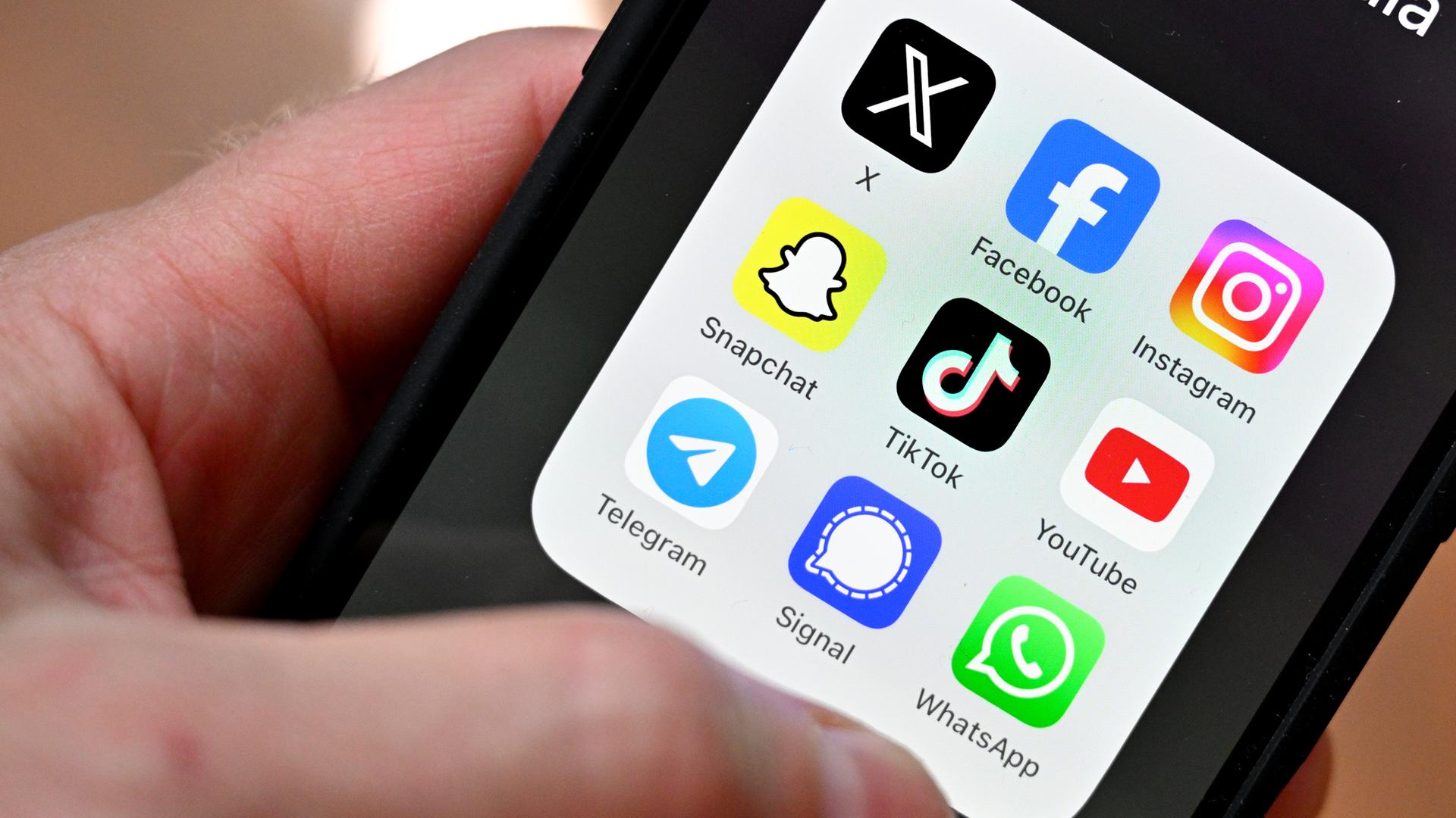 Eine Person hält ein Smartphone in der Hand, auf dem diverse Apps Sozialer Medien zu sehen sind.