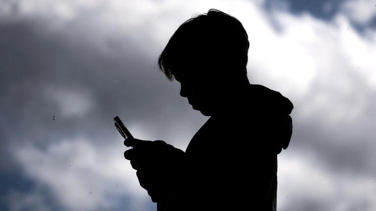 Ein kleiner Junge schaut auf ein Smartphone