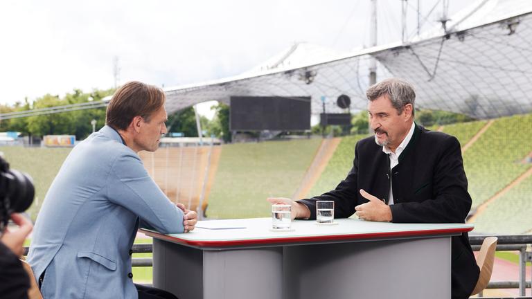 Wulf Schmiese und Markus Söder sitzen sich gegenüber und sind im Gespräch