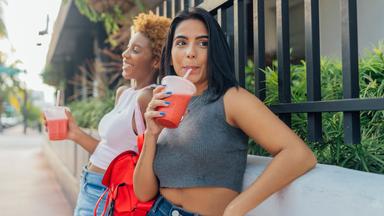 Zwei Frauen trinken einen Softdrink in der Stadt.