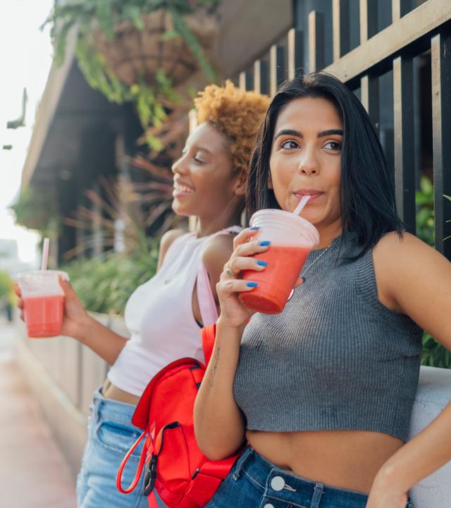 Zwei Frauen trinken einen Softdrink in der Stadt.
