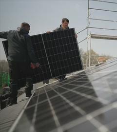 Zwei Männer bringen Solar-Panels an ein Dach an.