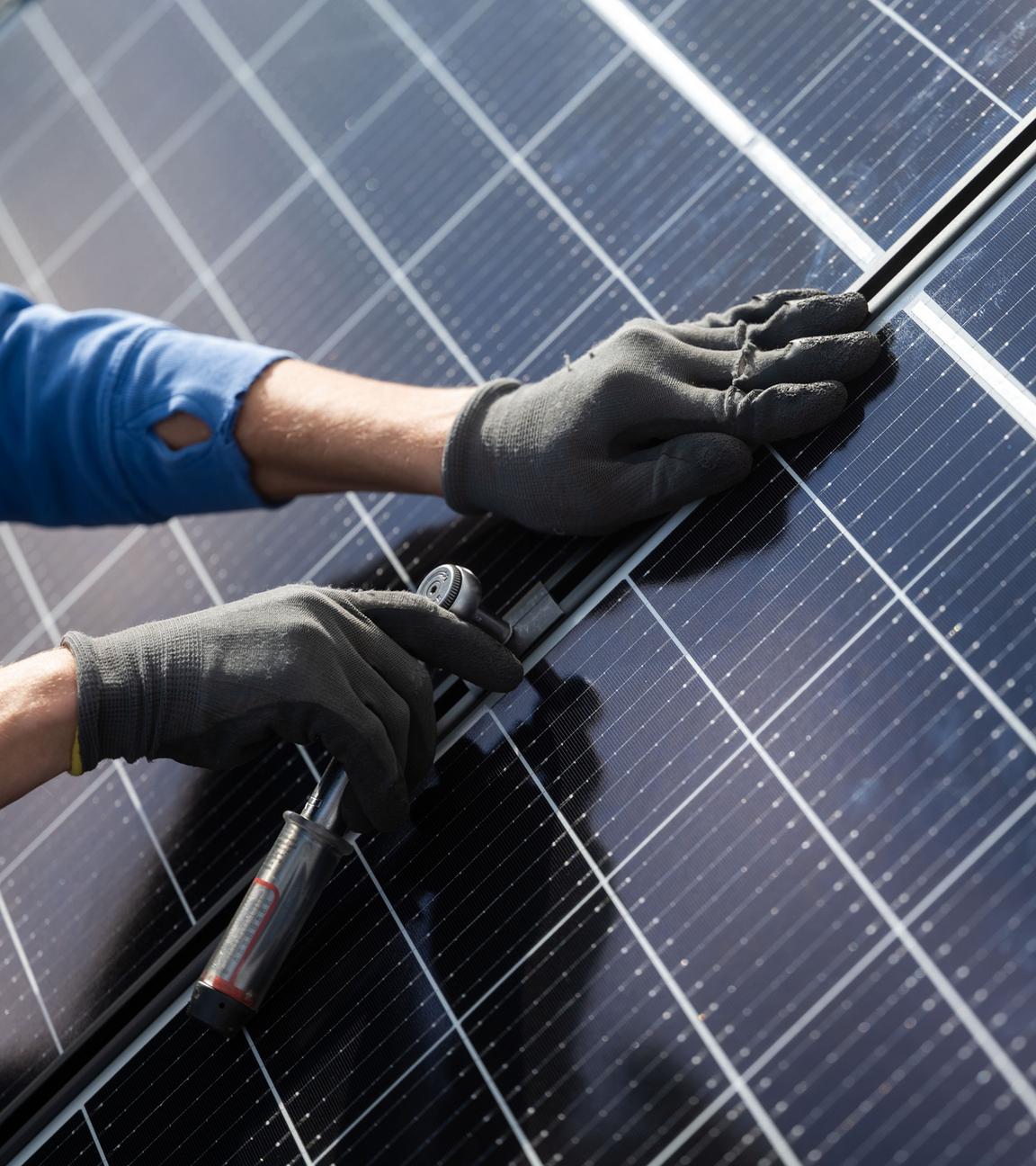 Ein Mann montiert Photovoltaikmodule auf dem Dach eines Wohnhauses.