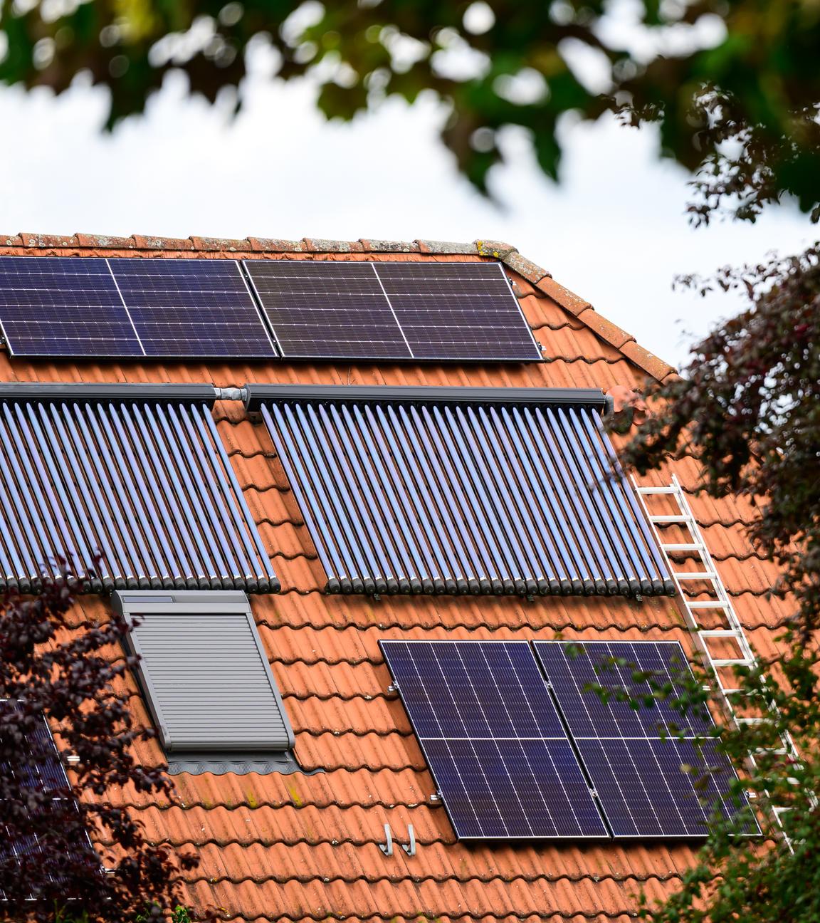 Solarmodule und Röhrenkollektoren auf einem Hausdach. 