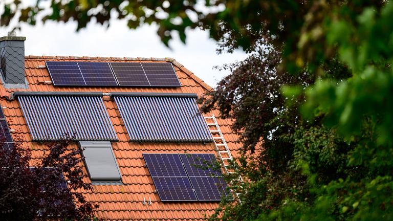 Solarmodule und Röhrenkollektoren auf einem Hausdach. 