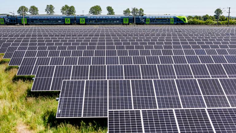 Schleswig-Holstein, Klein Rheide: Ein Regionalzug fährt an einem Solarfeld der Agri Photovoltaik, das in einem Moorgebiet steht, entlang.