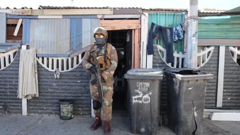 In Kapstadt kommt ein schwer bewaffneter Soldat aus einer Unterkunft in den Cape Flats