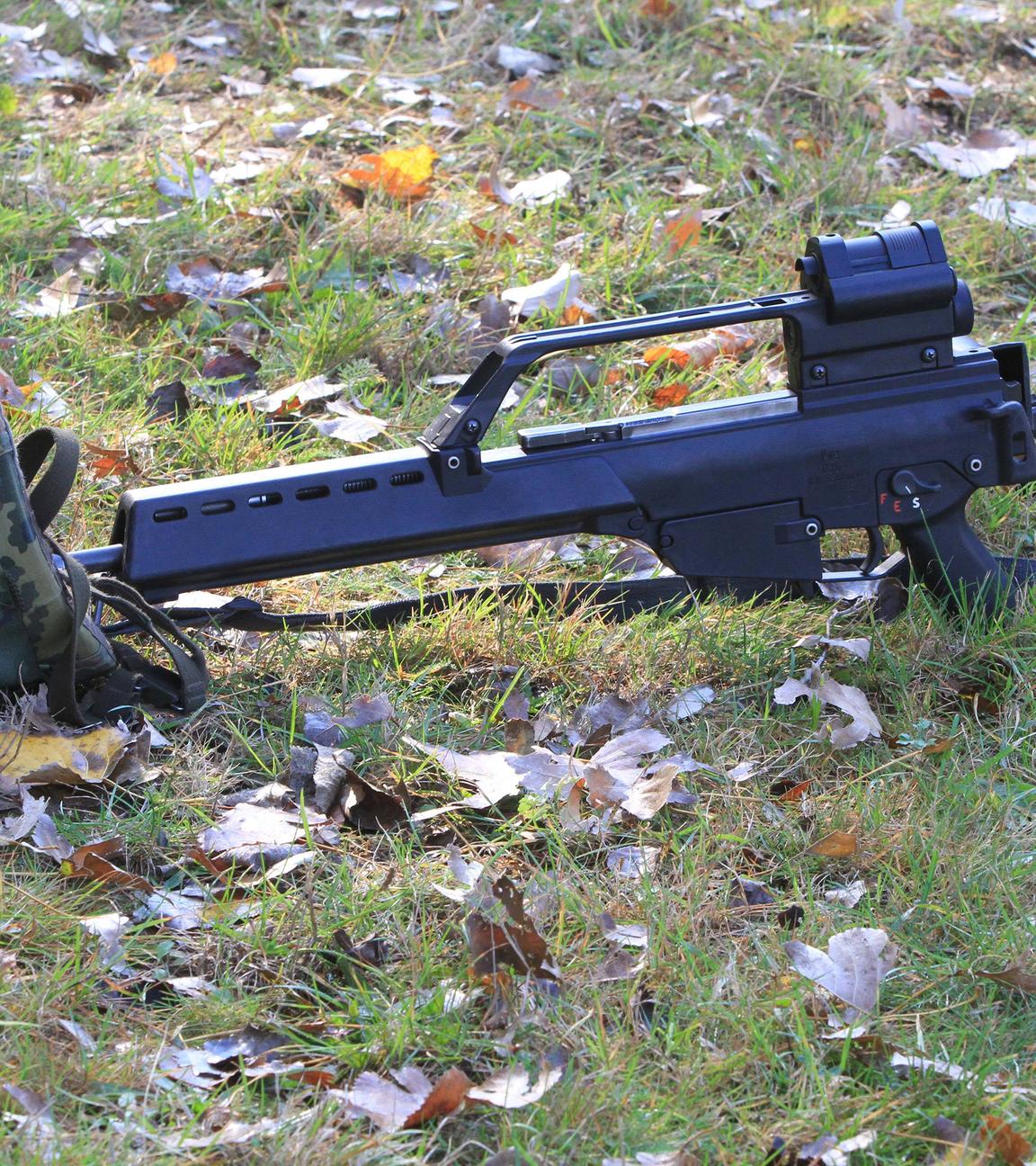 Ein Soldaten-Helm und ein Gewehr liegen im Gras.