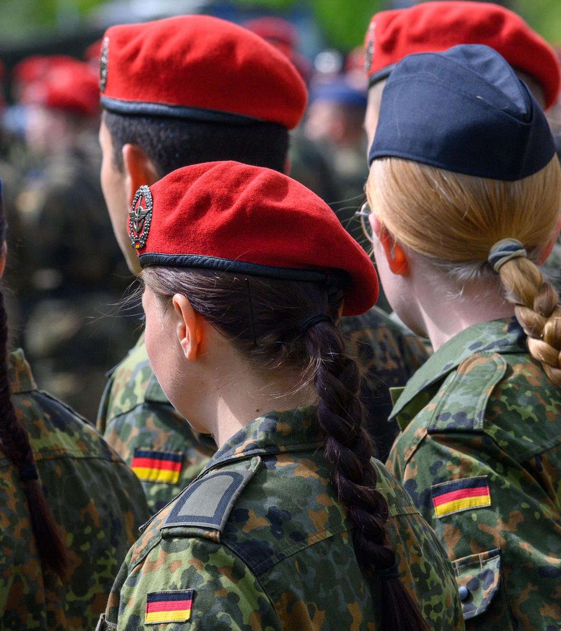 Rückansicht von weiblichen und männlichen Rekruten der Bundeswehr, die zum Gelöbnis stramm stehen.