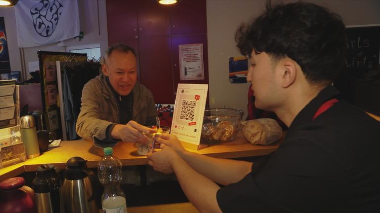 Mann reicht Mann ein Getränk