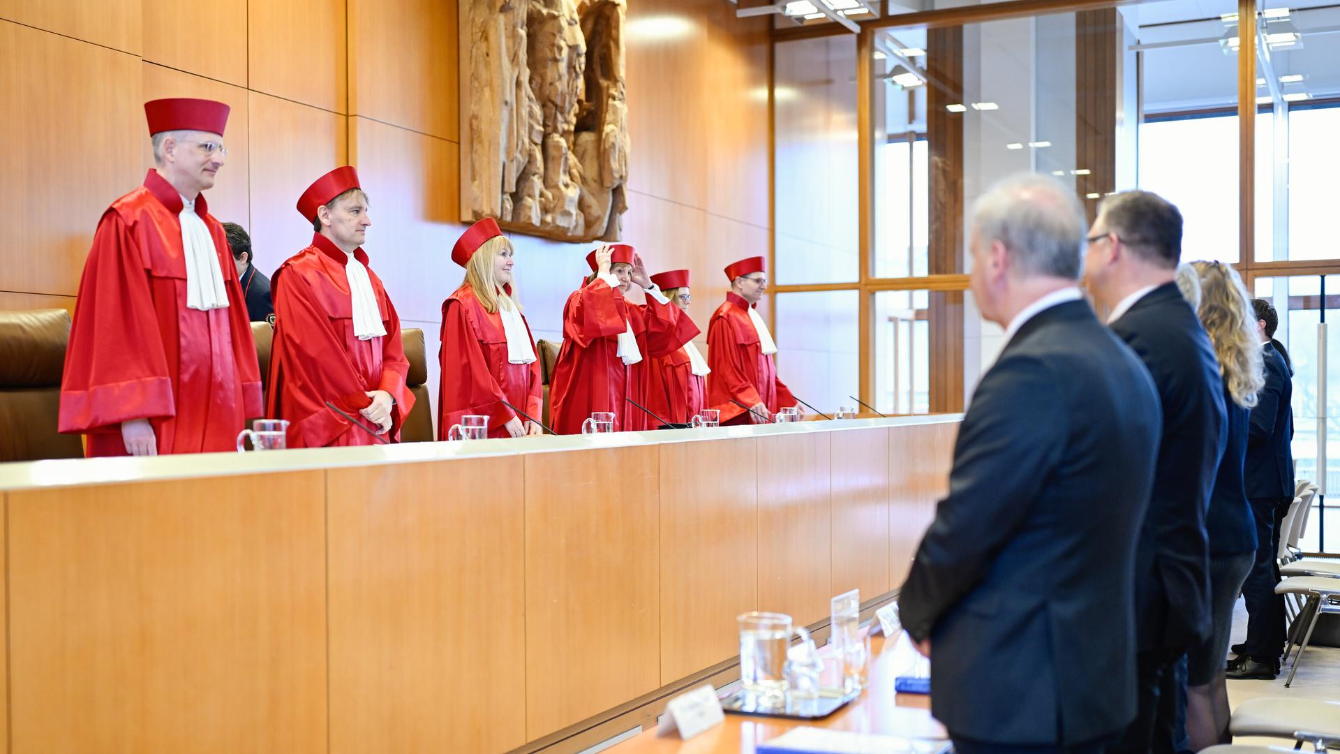 Vertreter des Zweiten Senats des Bundesverfassungsgerichts kommen in den Verhandlungssaal. Sie tragen rote Roben.