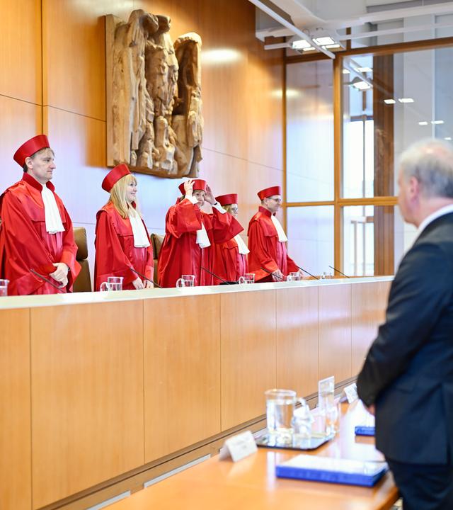 Vertreter des Zweiten Senats des Bundesverfassungsgerichts kommen in den Verhandlungssaal. Sie tragen rote Roben.