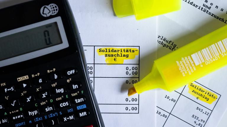 Steuerbescheid mit Taschenrechner und hervorgehobenes Wort 'Solidaritätszuschlag'