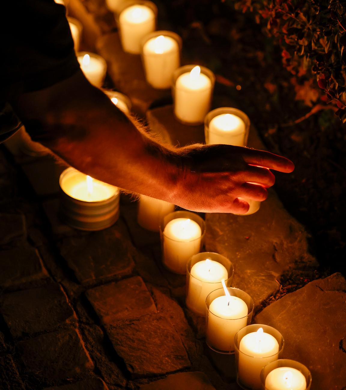 Bei der Trauerfeier an der Gedenktafel an der Evangelischen Stadtkirche, gedenken Menschen der Opfer des Terroranschlags und stellen brennende Kerzen auf.