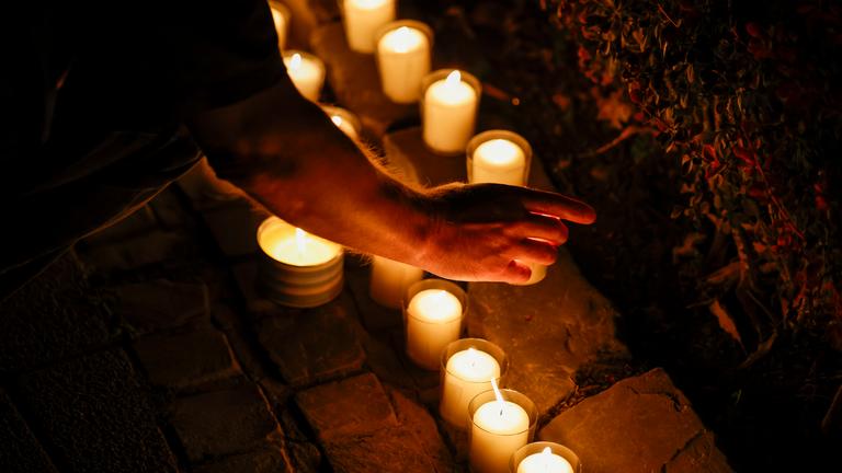 Bei der Trauerfeier an der Gedenktafel an der Evangelischen Stadtkirche, gedenken Menschen der Opfer des Terroranschlags und stellen brennende Kerzen auf.