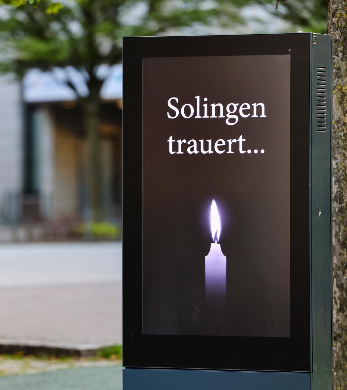 Solingen: Am Fronhof, dem Tatort des Messeranschlags von Solingen, steht der Schriftzug "Solingen trauert" und eine Kerze auf einem Bildschirm. 