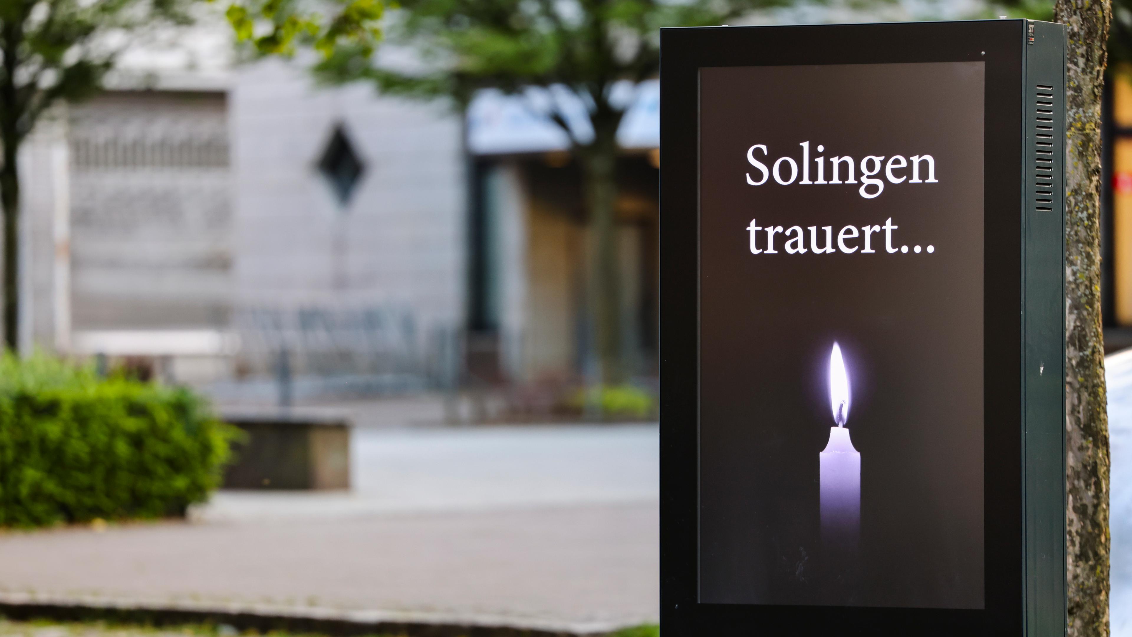 Solingen: Am Fronhof, dem Tatort des Messeranschlags von Solingen, steht der Schriftzug "Solingen trauert" und eine Kerze auf einem Bildschirm. 